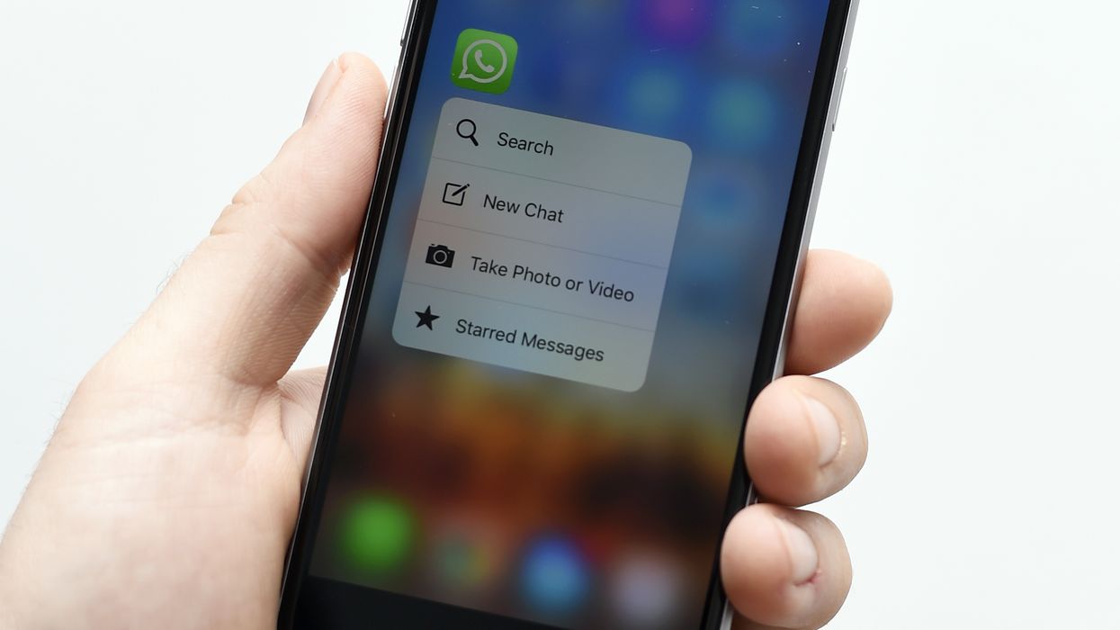 a hand holding a smartphone with the whatsapp icon