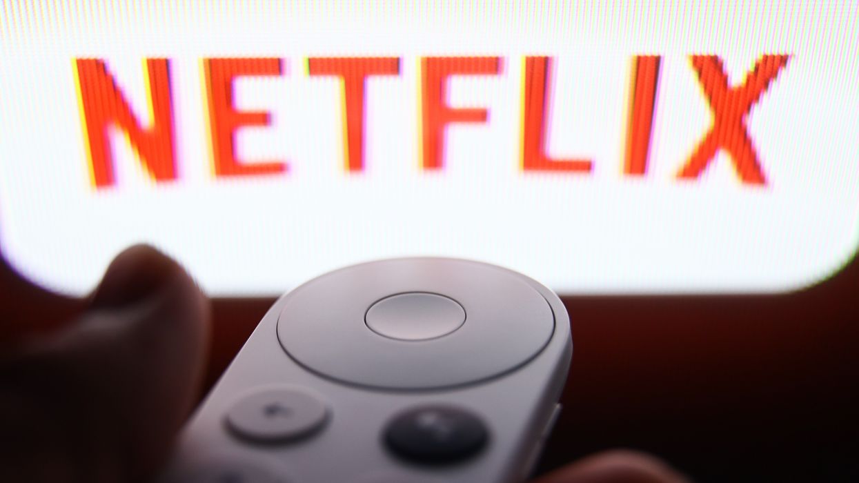 a hand holds a chromecast with google tv remote with the youtube logo on screen