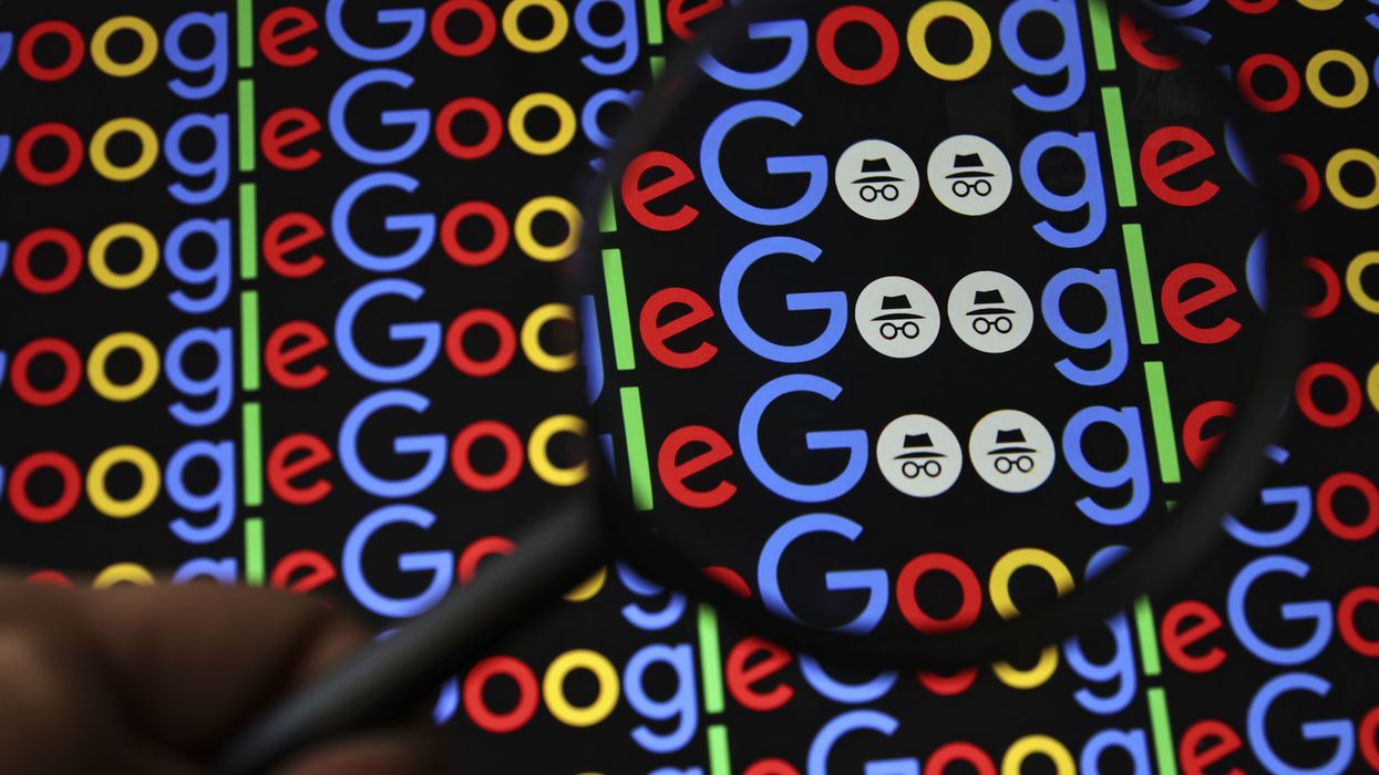a hand holds a magnifying glass over google logo to reveal the incognito mode icon