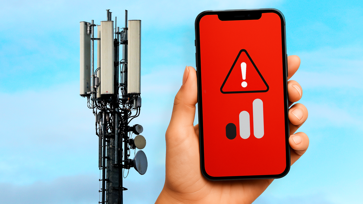 a hand holds a phone showing no signal with a 3G mast in the background