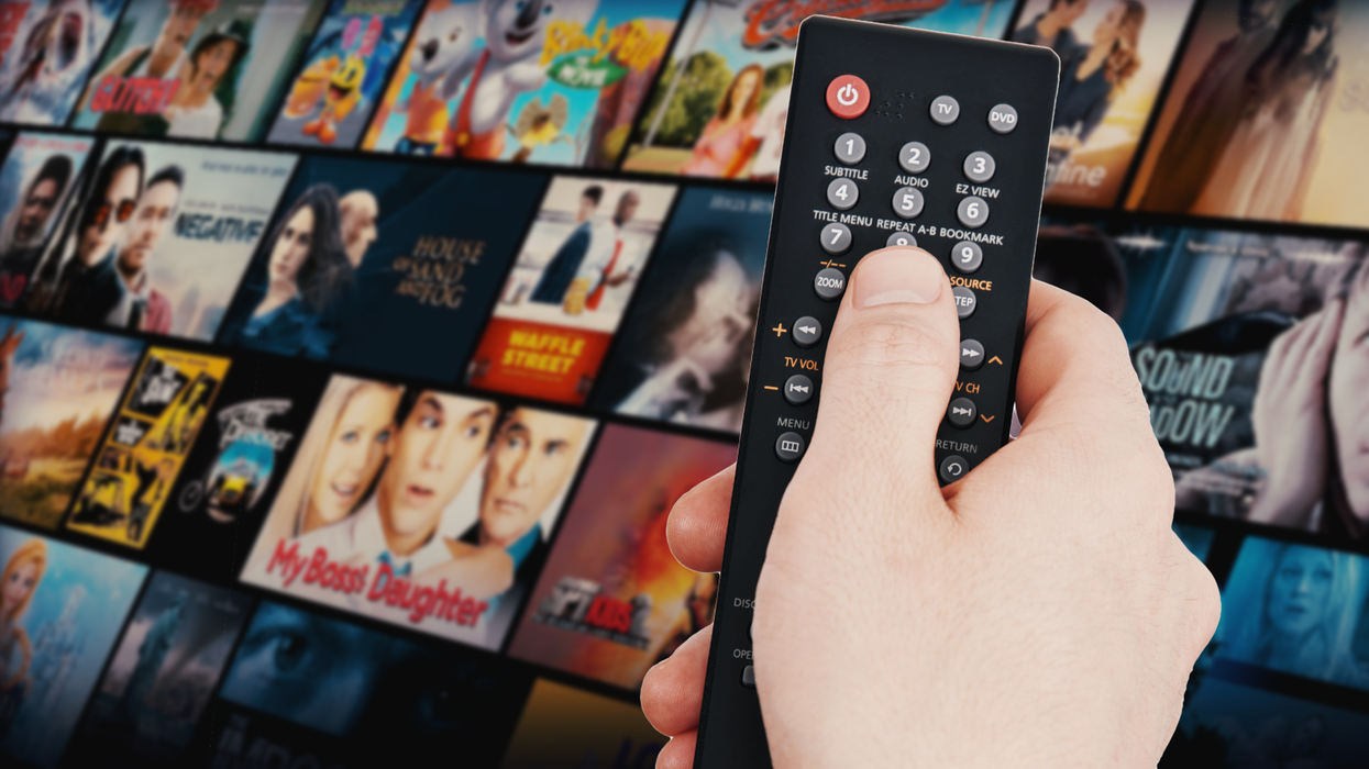 a hand holds a remote control with a tile of films tv shows and documentaries available to watch free of charge on fawesome streaming service