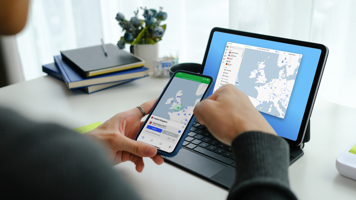 a hand holds a smartphone and looks at nordvpn on an iphone and ipad