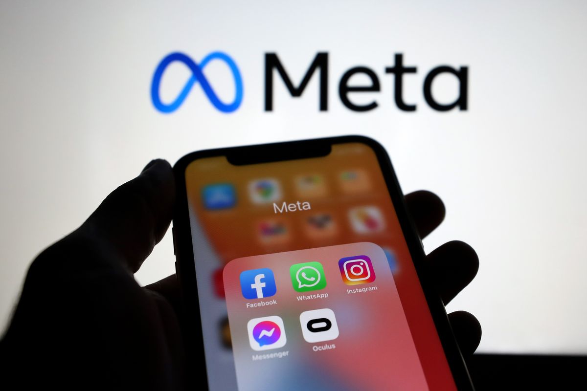 a hand holds a smartphone with a folder of apps owned by meta including instagram facebook whatsapp and messenger 