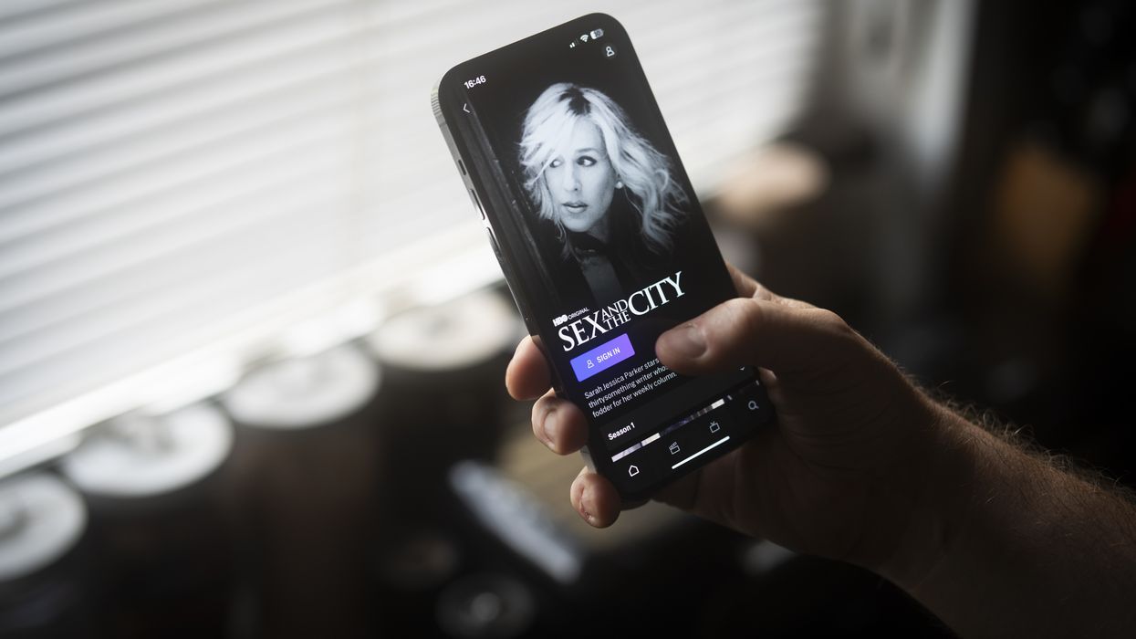 a hand holds a smartphone with sex and the city on-screen within the hbo max app
