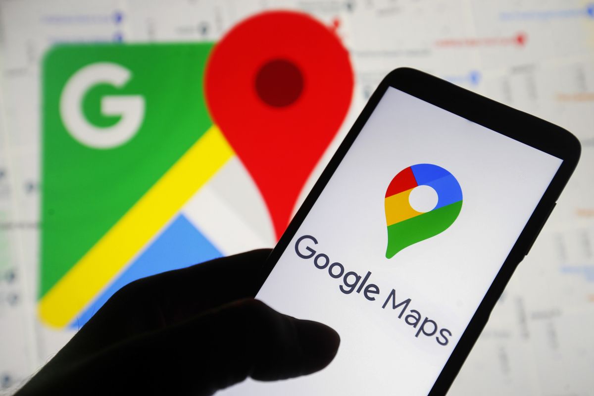 a hand holds a smartphone with the google maps icon on-screen