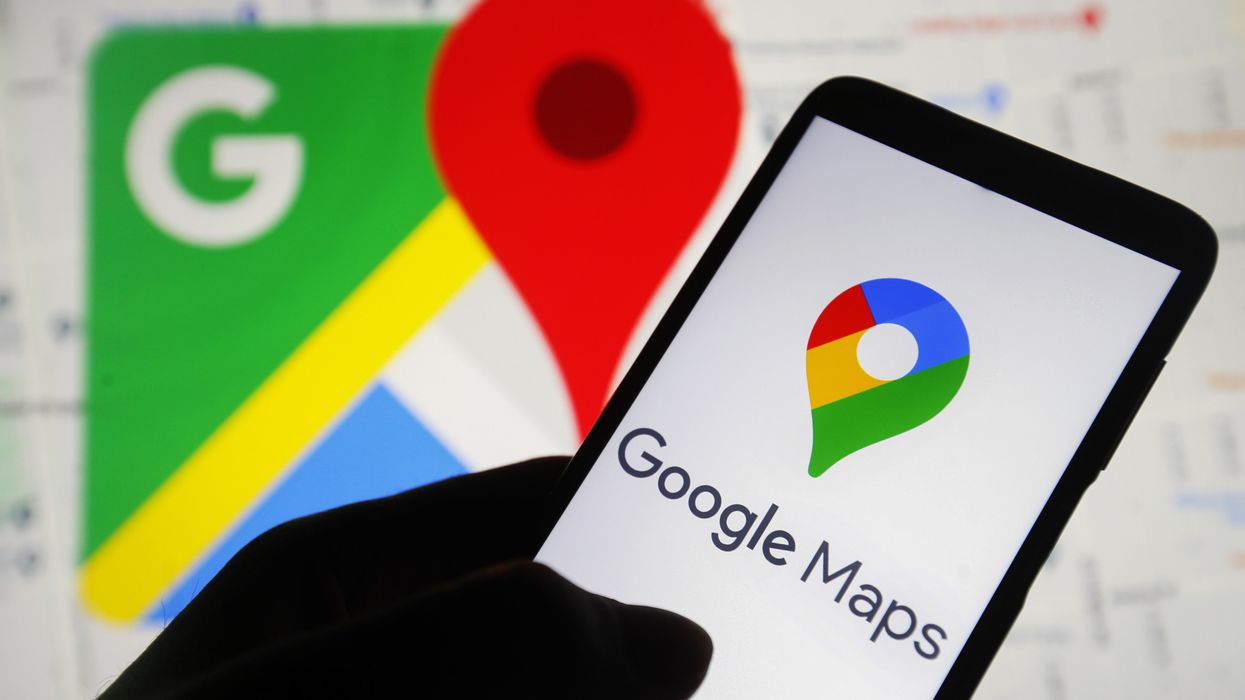 a hand holds a smartphone with the google maps icon on-screen
