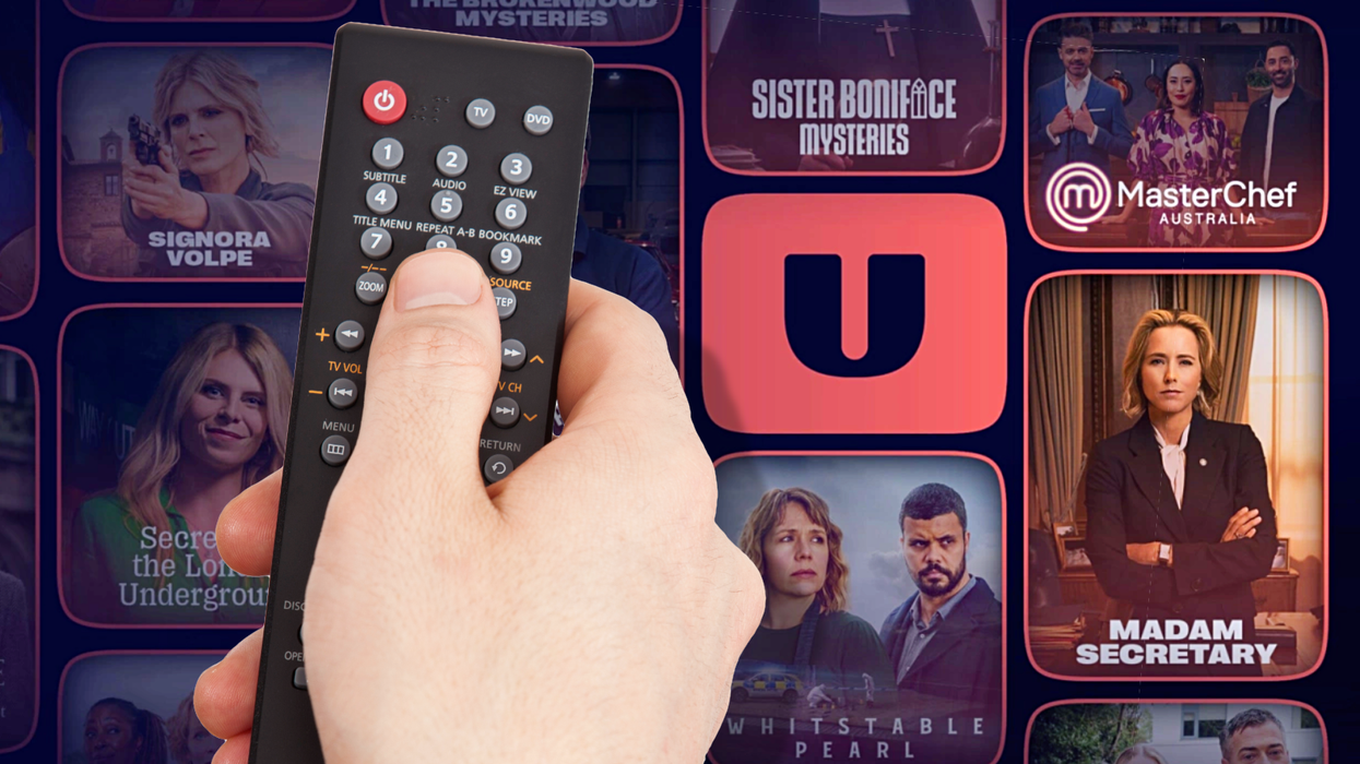 a hand holds a tv remote with the new U branded TV channels in the background