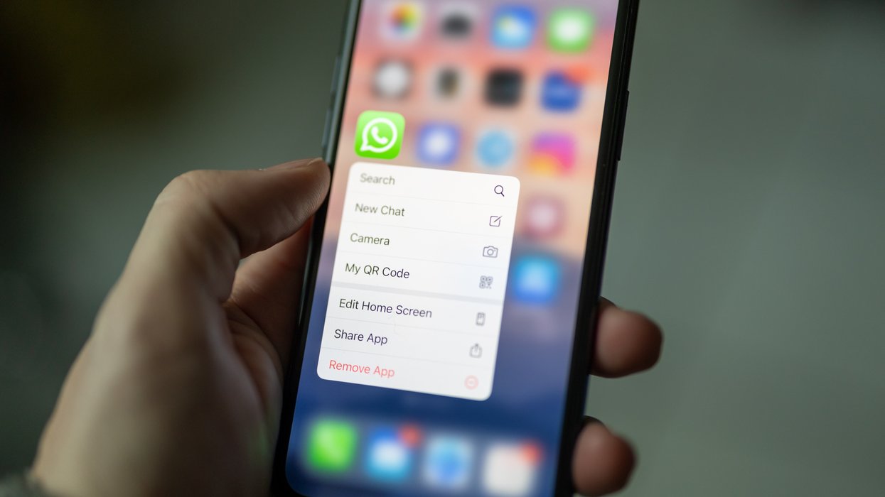 a hand holds an iphone with the whatsapp app icon prominently displayed on-screen