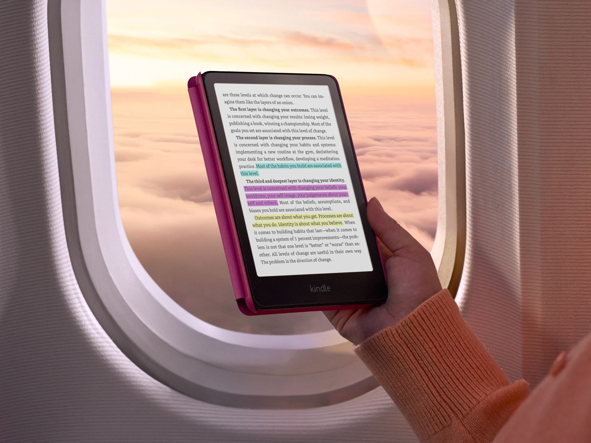 a hand holds the new kindle colorsoft on an aeroplane with colour highlights in pink, blue and yellow on-screen