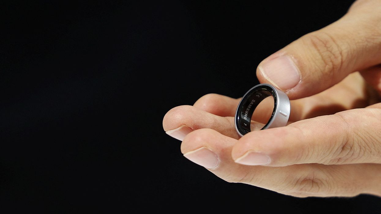 a hand holds the samsung galaxy ring in titanium silver