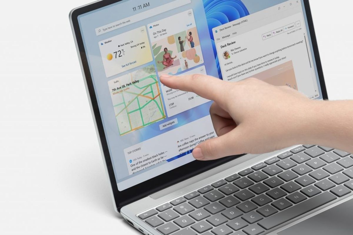 a hand is pictured using the touchscreen on a microsoft surface laptop 