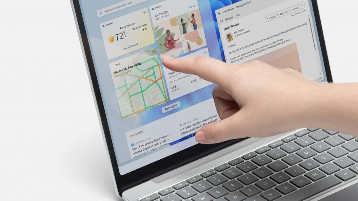 a hand is pictured using the touchscreen on a microsoft surface laptop
