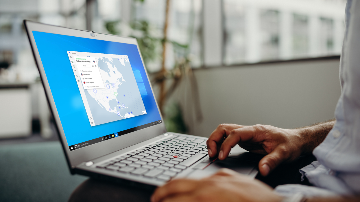 a hand navigates on the trackpad of a windows laptop with nordvpn visible on-screen
