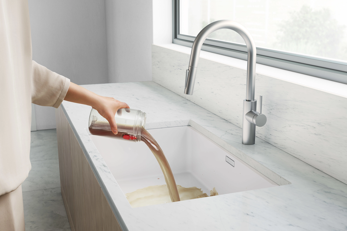 a hand pours away dirty water from the reservoir built into the dyson wash g1