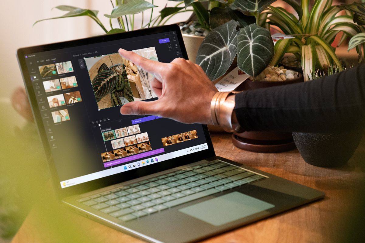 a hand uses the touchscreen on a green microsoft surface laptop 5 running windows 11 