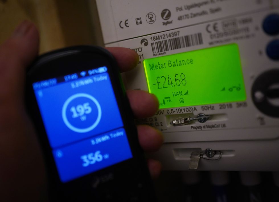 A handheld SSE smart meter for household energy usage is held next to an electricity meter. Families across Great Britain will find out on Friday how tough energy bills will be this winter but they may have to wait to discover what the Government will do to help Picture date: Thursday August 25, 2022.