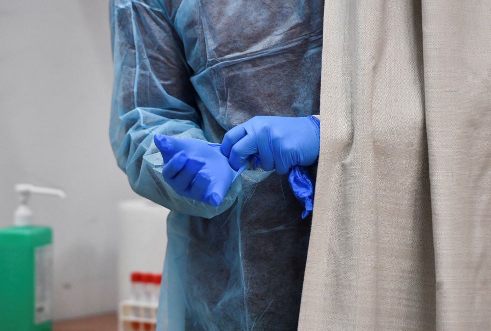 A health worker puts on gloves ahead of conducting coronavirus disease (COVID-19) tests, after Italy has ordered COVID-19 antigen swabs and virus sequencing for all travellers coming from China, where cases are surging, at the Malpensa Airport in Milan, Italy, December 29, 2022. REUTERS/Jennifer Lorenzini