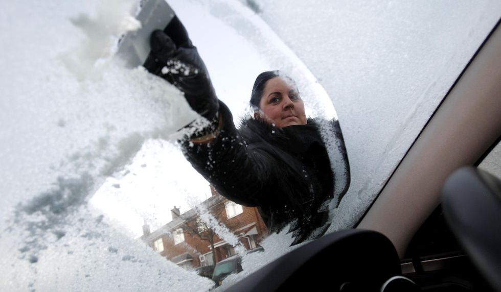 A lady scrapes ice from her car after the cold winter arrived in Liverpool.