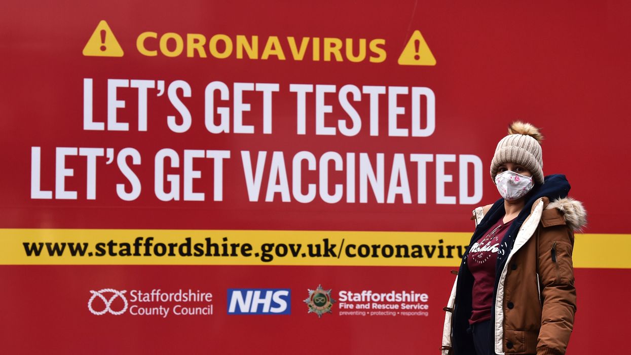 A lady walks coronavirus test centre which displays a sign saying 'Lets get tested, lets get vaccinated