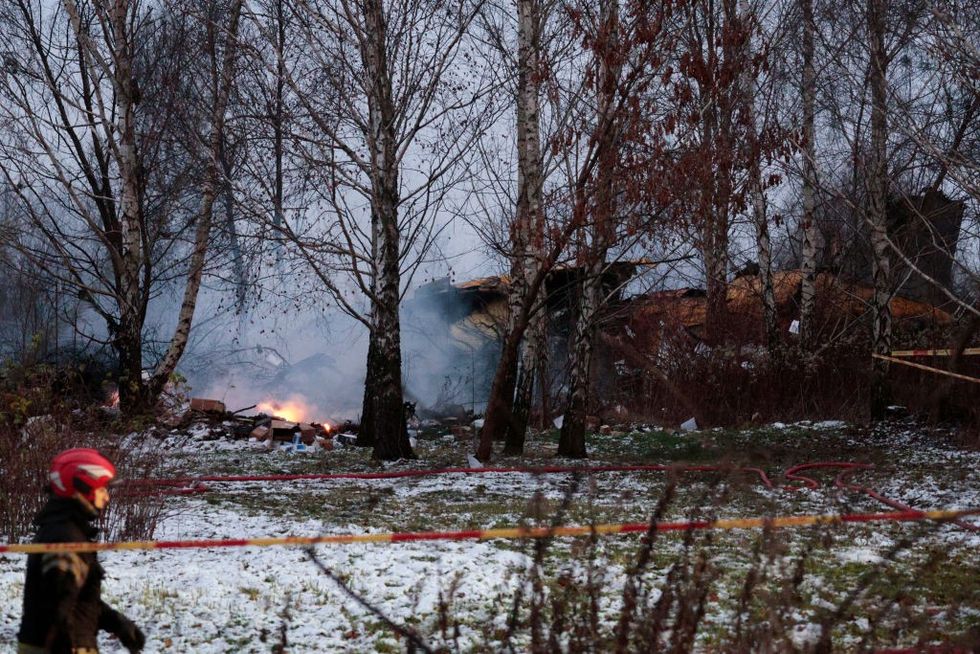 A Lithuanian rescuer walks past the wreckage of a cargo plane following its crash near Vilnius International Airport