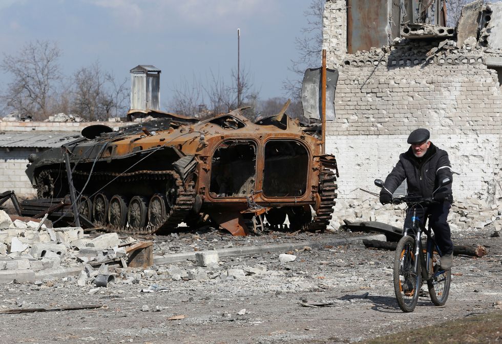A local resident rides a bicycle past a charred armoured vehicle during Ukraine-Russia conflict in the separatist-controlled town of Volnovakha in the Donetsk region, Ukraine March 15, 2022. REUTERS/Alexander Ermochenko
