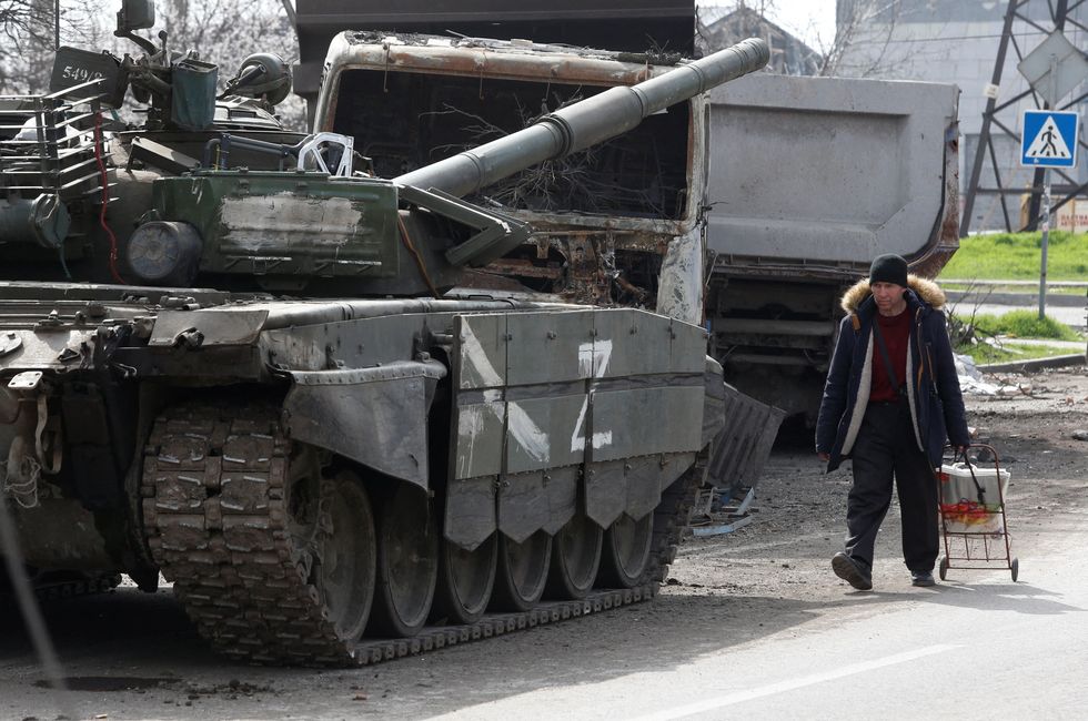 A local resident walks next to a tank of pro-Russian troops during Ukraine-Russia conflict in the southern port city of Mariupol.