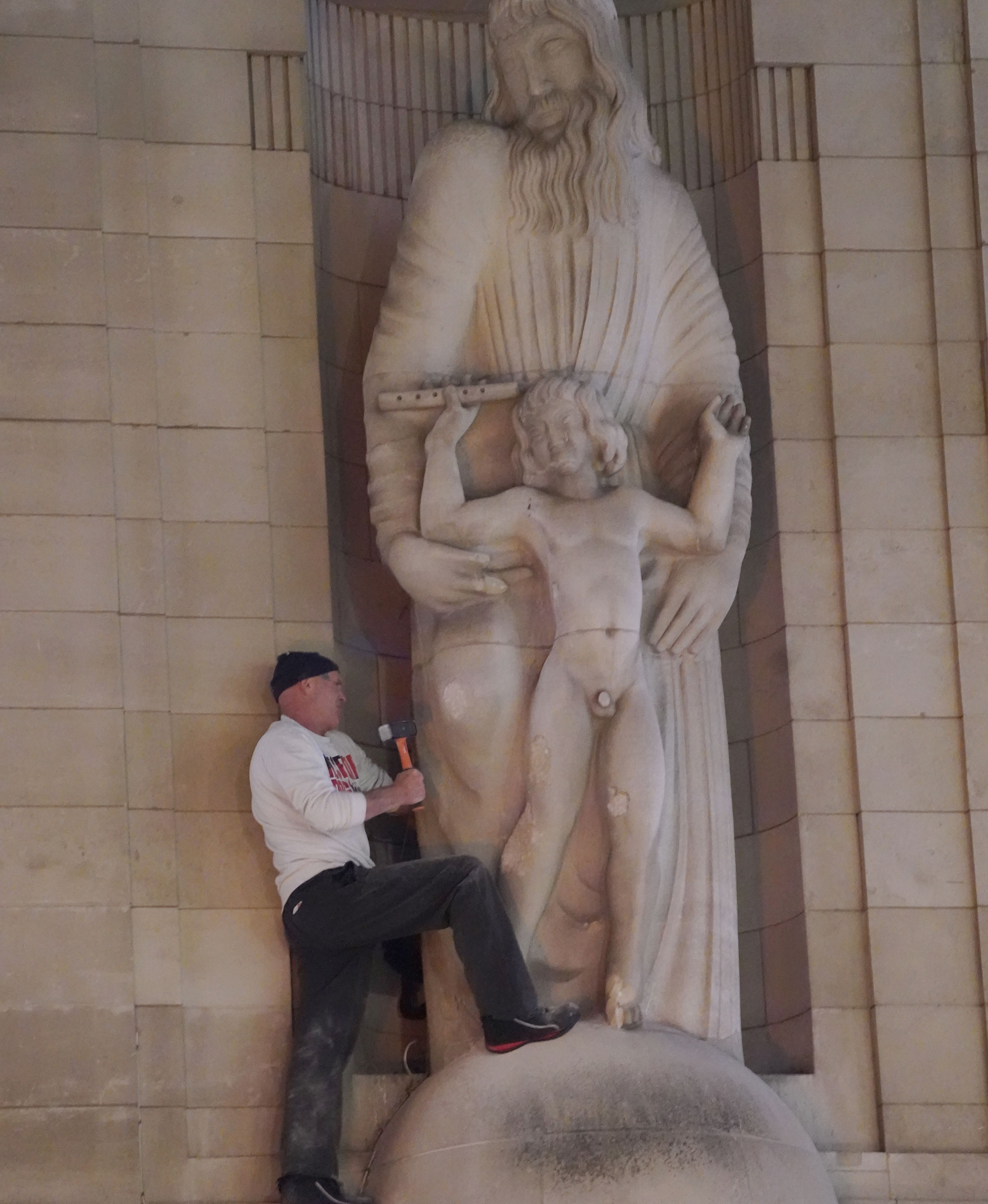 A man after he climbed onto the statues Prospero and Ariel from Shakespeare's play The Tempest by the sculptor Eric Gill outside of the BBC's headquarters in central London and hit them with hammer.