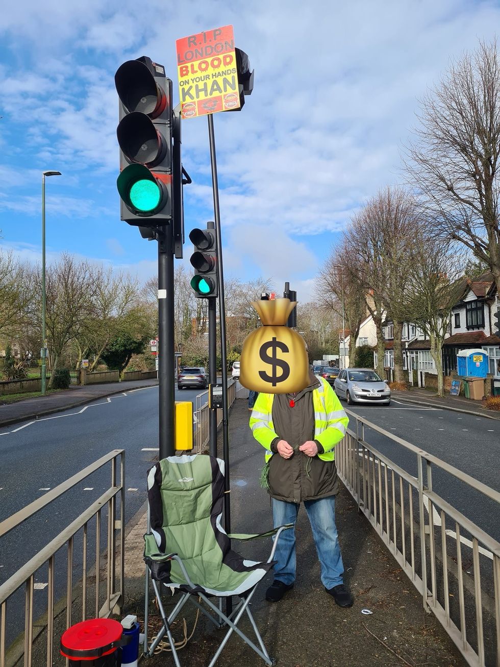 A man blocking a Ulez camera with a sign