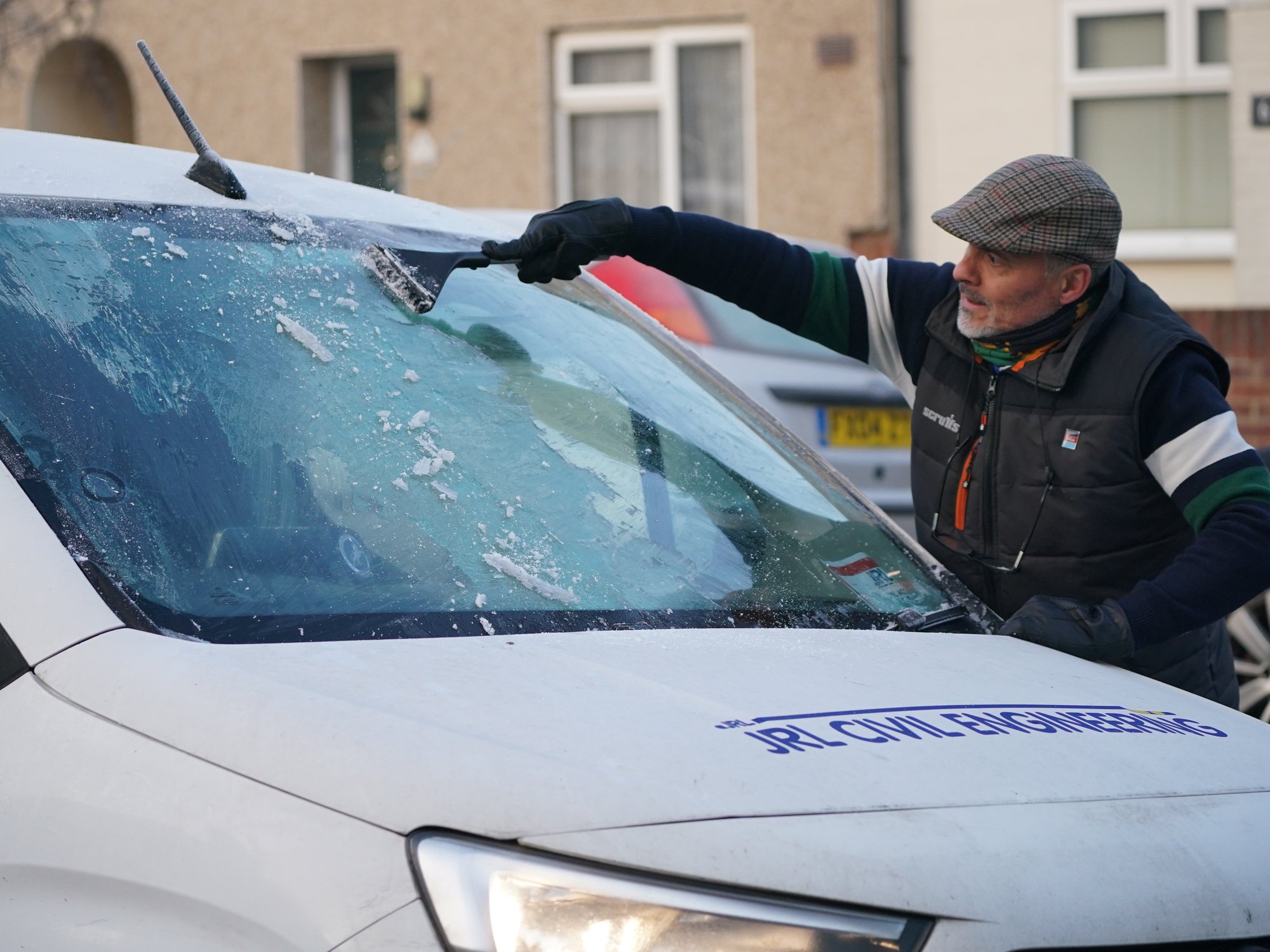 A man clearing windscreen frost