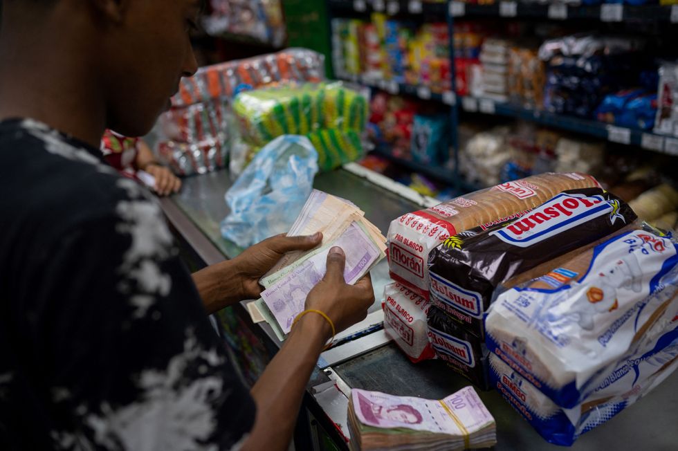 A man counts Bolivar bills to buy groceries in a supermarket