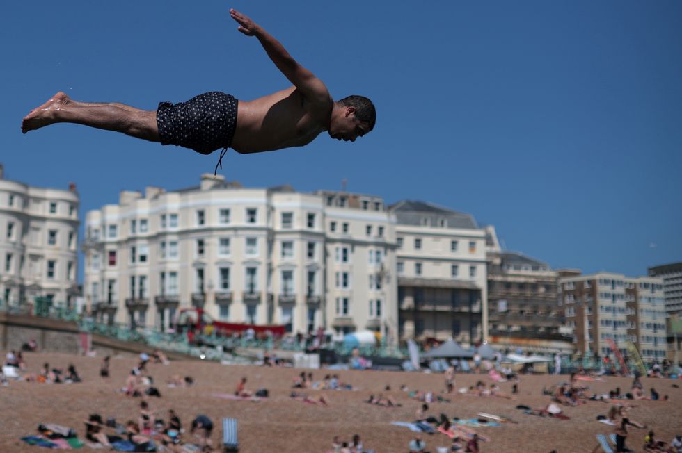 A man dives into the sea as people enjoy the hot weather on Brighton beach.