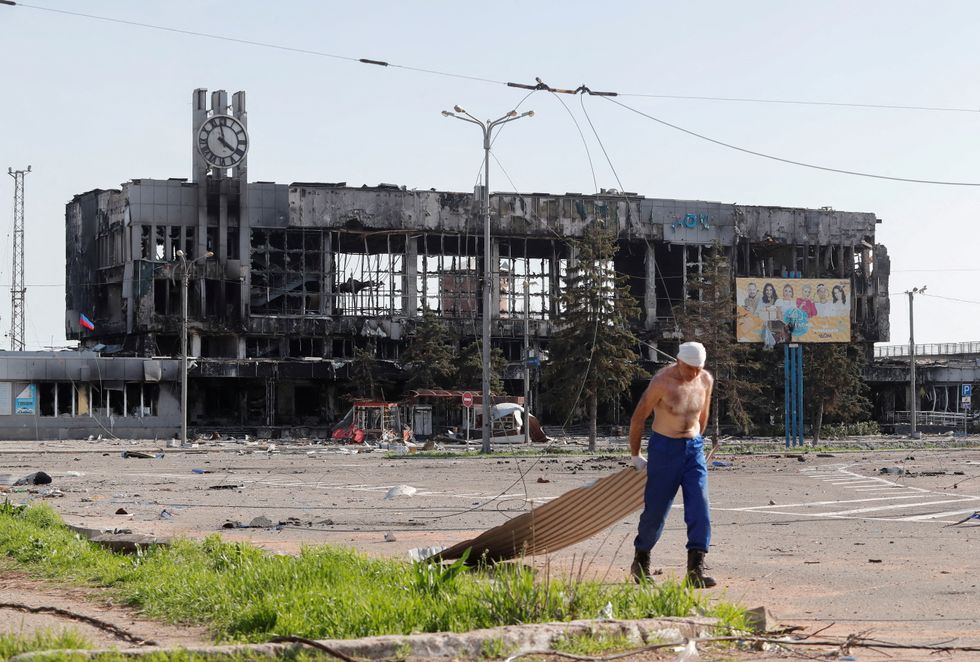 A man drags metal board near a railway station building destroyed during the Ukraine-Russia conflict in the southern port city of Mariupol.