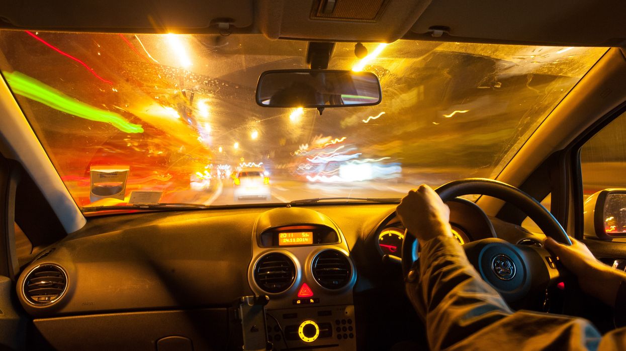A man driving a car in traffic at night