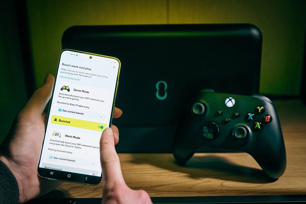a man enables Game Mode from a smartphone app linked to the EE WiFi router