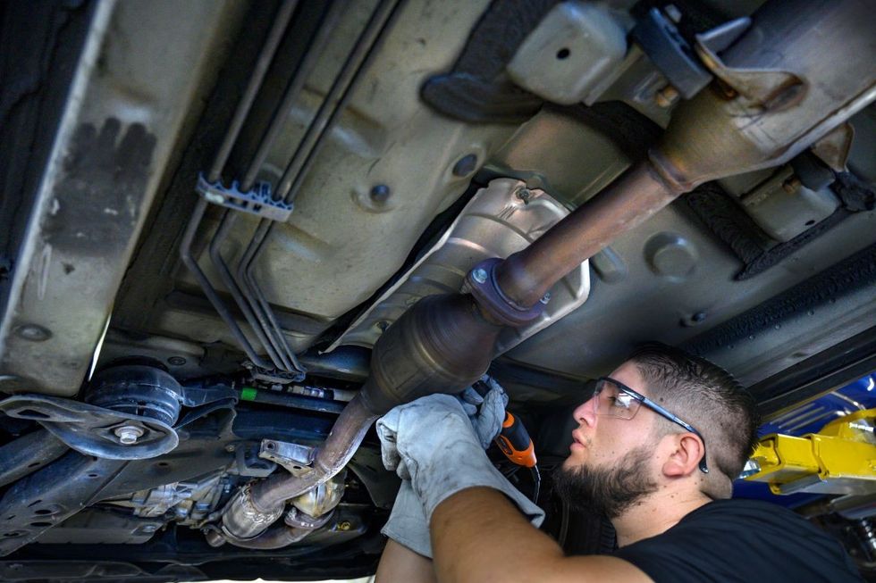 A man engraving a car's catalytic converter