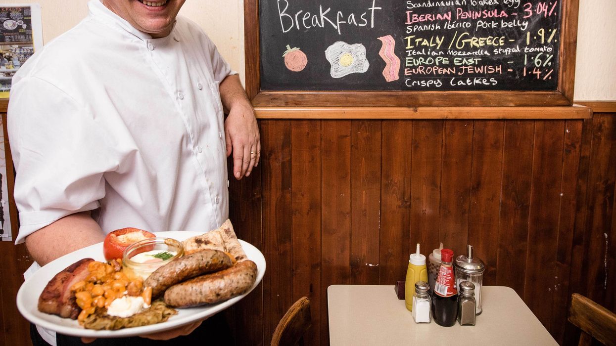 A man holding a plate with a full English breakfast on it