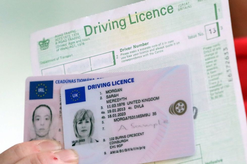 A man holding a UK driving licence and driving licence application form