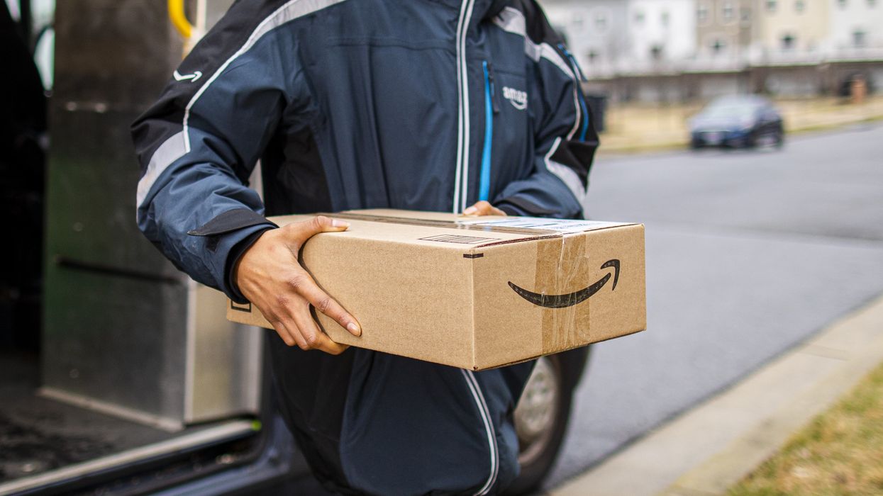 a man holds an amazon box with the prime logo as he walks out of a van
