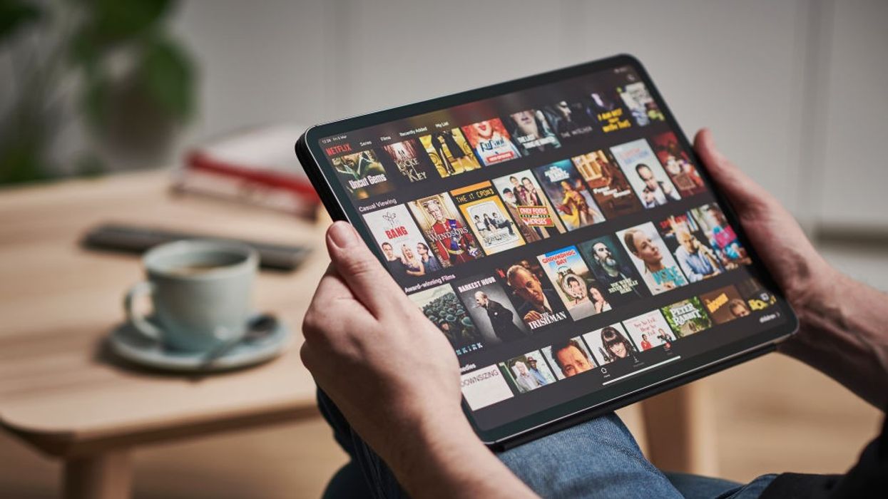 a man holds an ipad with the netflix app showing on screen