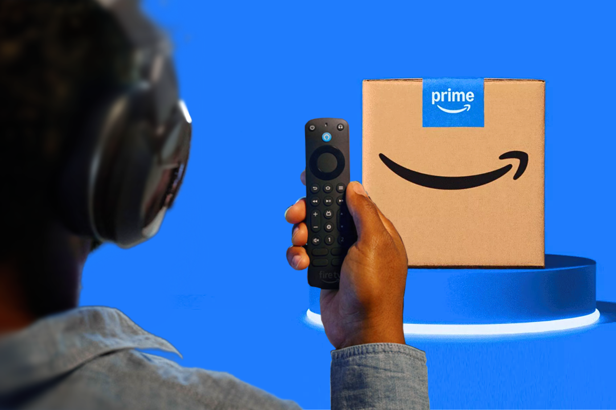 a man holds up the fire tv stick alexa pro remote with a prime delivery box seen in the background