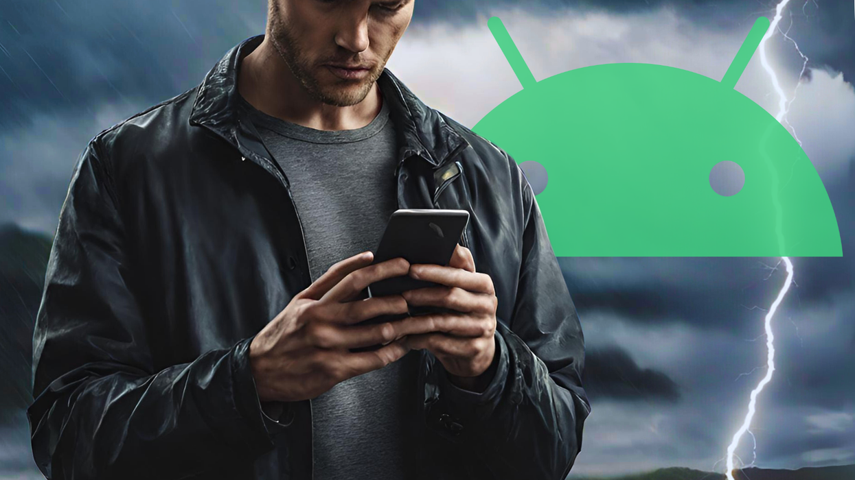 a man in a rain coat holds out a smartphone with a stormy background behind him