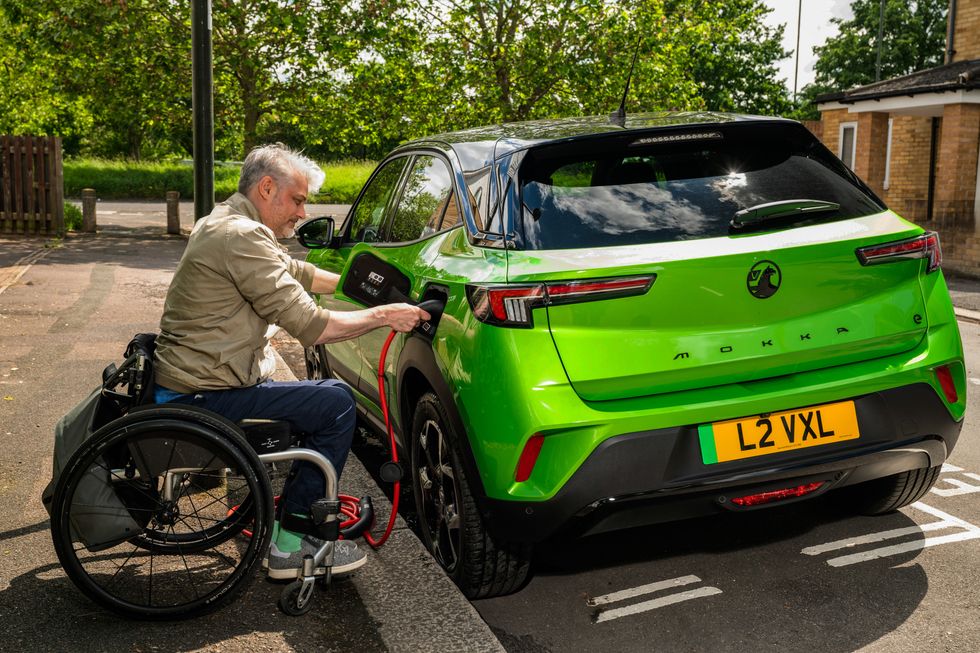 A man in a wheelchair plugs in a Vauxhall Mokka EV