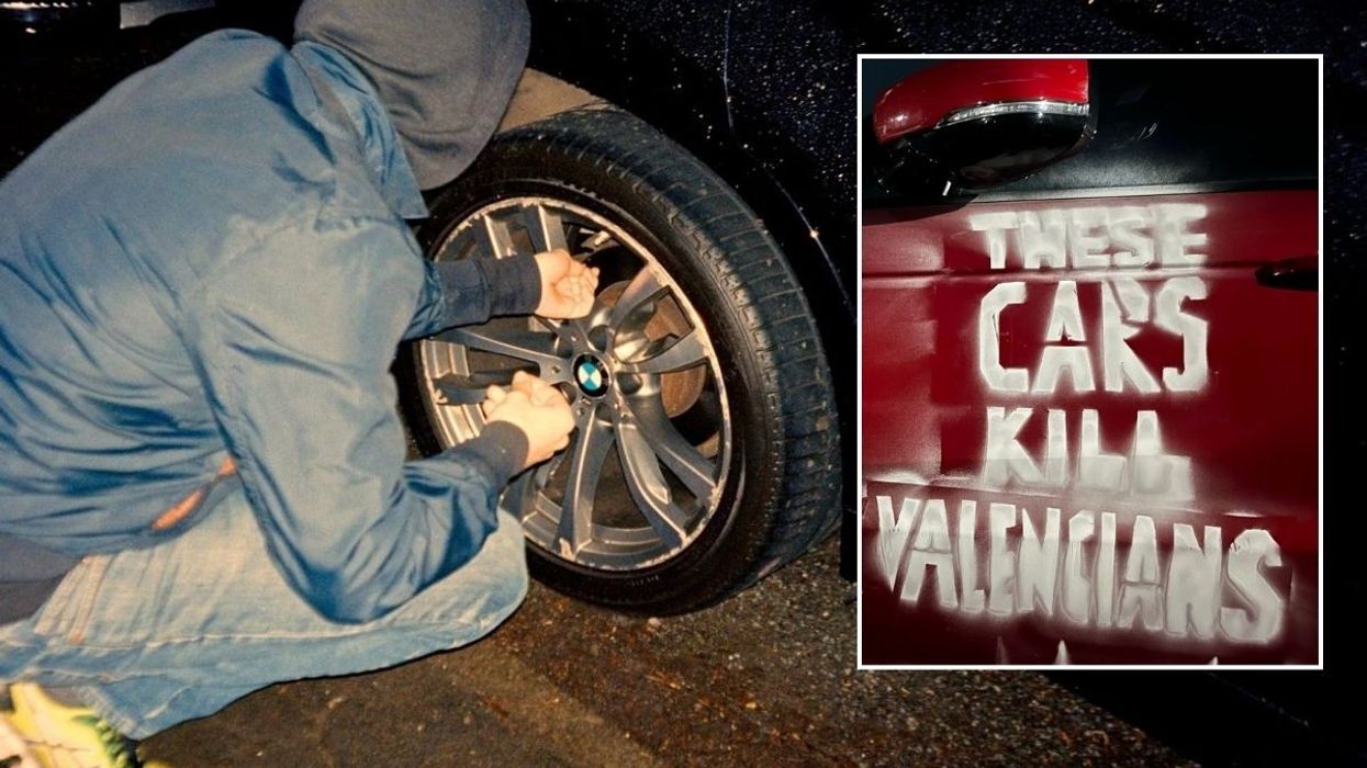 A man letting down the tyres of an SUV and a spray-painted message of 'These cars kill Valencians'