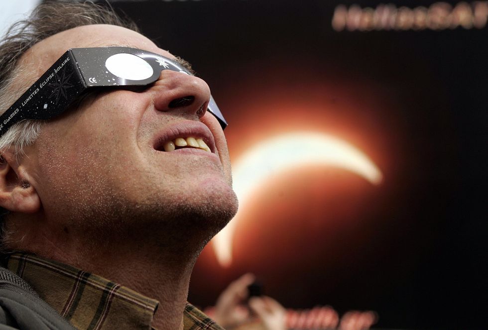 A man looks at the sun through a special glasses