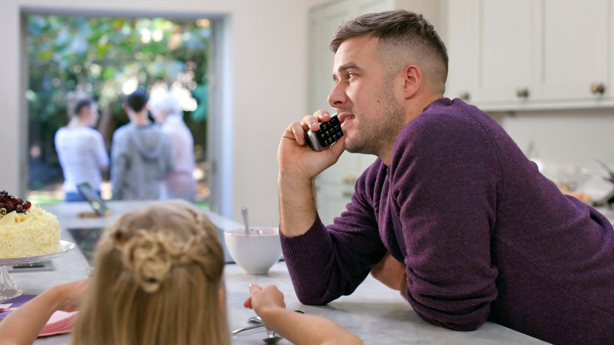 a man makes a call on a BT digital voice handset in a busy kitchen