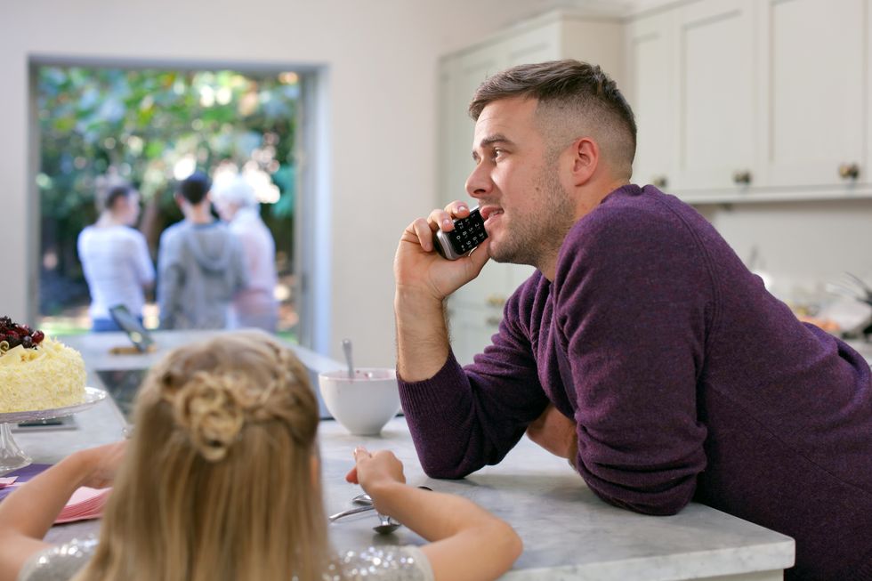 a man makes a call on a BT digital voice handset in a busy kitchen 