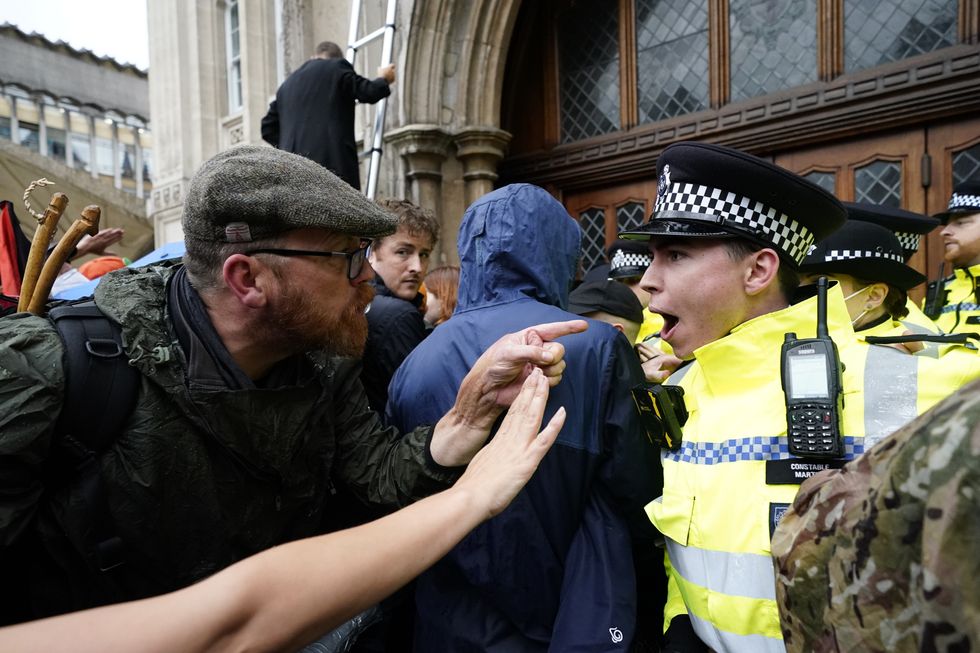 A man points in the face of a police officer as members of Extinction Rebellion stage a protest outside the Guildhall, London.