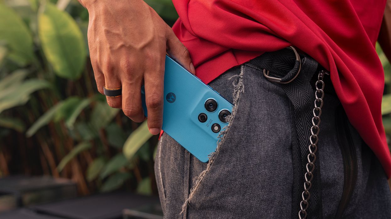 a man puts a blue motorola g75 5g in the pocket of their jeans