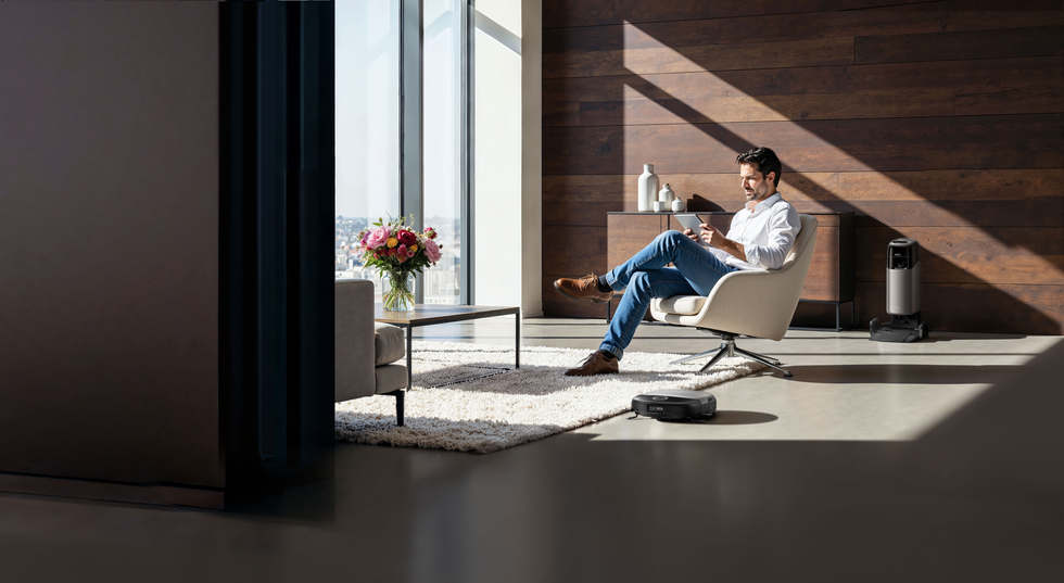 a man reclines while the Omni S2 robot vacuum cleans around him