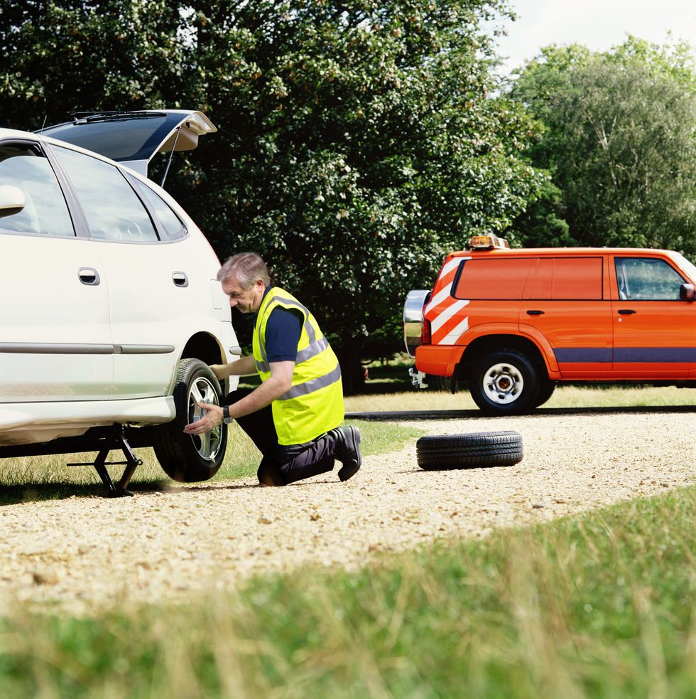A man replacing a tyre of a broken down vehicle